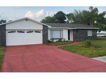 Charming single-story home with a red driveway, grey stone accents, and a two-car garage at 1328 Highland Cir, Kissimmee, FL 34744