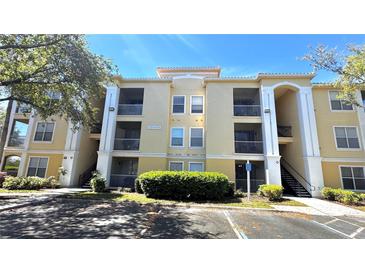 Three-story condo building with yellow siding, white trim, and exterior stairs and patios at 1400 Lake Shadow Cir # 10105, Maitland, FL 32751