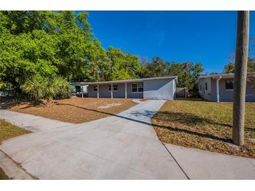 Charming single-story home featuring a long driveway and mature trees on a sunny day at 4121 Caywood Cir, Orlando, FL 32810