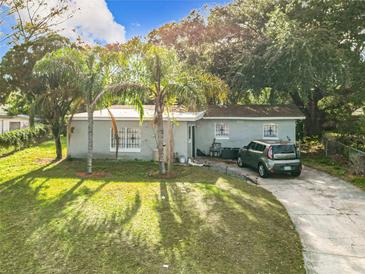 Charming single-story home with lush front lawn, palm trees, and driveway at 444 Sunnyview Cir, Orlando, FL 32810