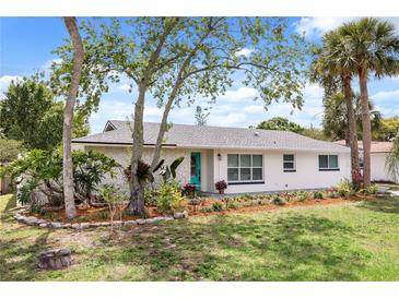 Charming single-story home with a stone facade, lush landscaping, and a bright turquoise front door at 7320 Fieldcrest Ave, Winter Park, FL 32792