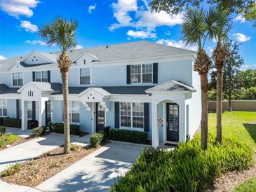Charming townhome featuring a light blue exterior, palm trees, and well-maintained landscaping at 7666 Sir Kaufmann Ct, Kissimmee, FL 34747
