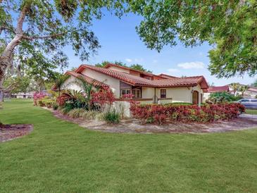 Charming villa featuring a red tile roof, lush landscaping, and a well-manicured lawn in a vibrant setting at 112 Coventry Ln, Haines City, FL 33844