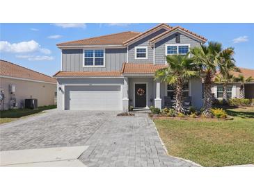 Beautiful two-story home featuring a well-manicured lawn, neutral color palette, and a paved driveway leading to a two-car garage at 1158 Oak Bluff Dr, Davenport, FL 33837