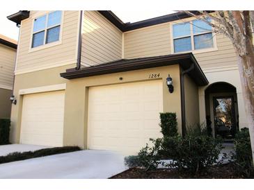 Charming townhouse featuring attached garages, manicured landscaping, and a welcoming entrance at 1284 Pavia Dr, Apopka, FL 32703
