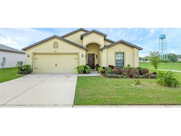Charming one-story home with a well-manicured lawn and attached two-car garage on a sunny day at 1924 Piedmont Ct, Mascotte, FL 34753