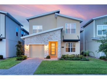 Charming two-story home with a stone facade, well-manicured lawn, and a brick driveway leading to an attached garage at 2805 Bookmark Dr, Kissimmee, FL 34746