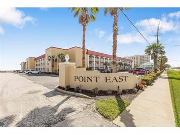 Inviting view of Point East exterior featuring a manicured lawn and swaying palm trees at 3801 S Atlantic Ave # 114, New Smyrna Beach, FL 32169