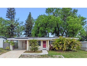 Charming single-story home with a well-manicured lawn, mature trees, and a welcoming red front door at 6031 W Ridgewood Ave, Orlando, FL 32835