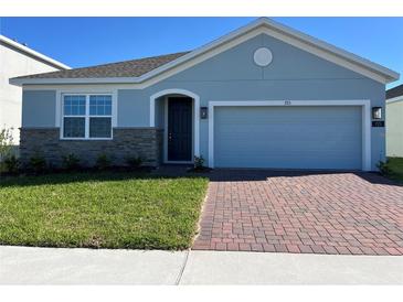 Charming single-story home featuring a two-car garage, brick driveway, and well-manicured lawn at 725 Ginger Dr, Haines City, FL 33844