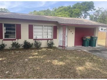 Charming single-story home with a red-trimmed roof, attached garage, and small front yard at 904 Hickory Ave, Fruitland Park, FL 34731
