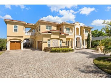 Stunning Mediterranean-style home showcasing a tile roof, balconies, porte-cochere and a brick paver driveway at 225 Magnolia St, Windermere, FL 34786