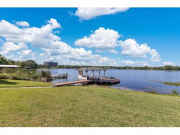 Expansive lake view featuring a dock with a covered sitting area and lush green landscaping at 673 Balmoral Rd, Winter Park, FL 32789