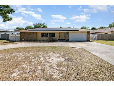 Charming single-story home featuring a stone facade, solar panels, a two-car garage and a curved driveway at 690 S Lakemont Ave, Winter Park, FL 32792