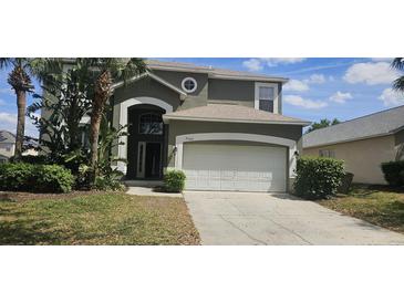 Charming two-story home featuring an attached two car garage and well maintained landscaping with palm trees at 8500 Palm Harbour Dr, Kissimmee, FL 34747