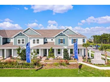 A beautiful two-story townhouse with blue accents, a covered porch, and professionally landscaped grounds at 13532 Autumn Harvest Ave, Winter Garden, FL 34787