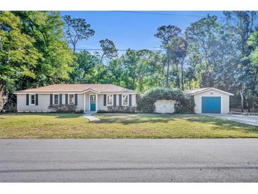 Charming single-story home with a detached garage and well-maintained lawn and mature landscaping at 225 N Phippen Ave, Deland, FL 32724
