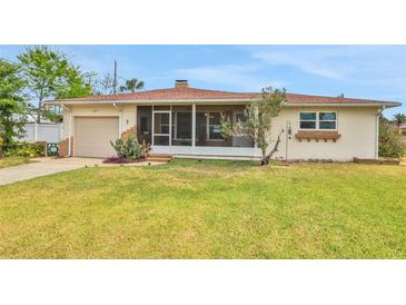 Charming single-story home featuring a screened front porch, lush lawn, and an attached one-car garage at 2811 S Peninsula Dr, Daytona Beach, FL 32118