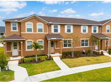 Exterior view of townhomes featuring a manicured lawn and lovely landscaping at 2962 Firebush Way, Clermont, FL 34711