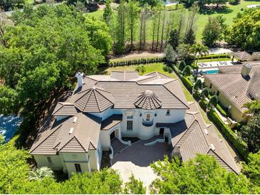 Stunning aerial view of a luxury home with a tile roof, a pool, and lush landscaping at 5067 Latrobe Dr, Windermere, FL 34786