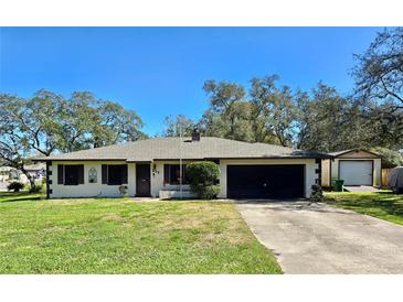 Charming one-story home with a lush green lawn, mature trees, long driveway, and a single-car garage at 527 Leland Dr, Deltona, FL 32725