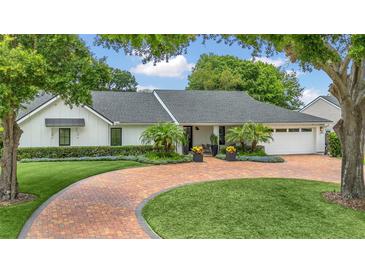 Beautiful white home featuring a circular driveway, palm trees, and manicured landscaping at 7455 Sparkling Lake Rd, Orlando, FL 32819