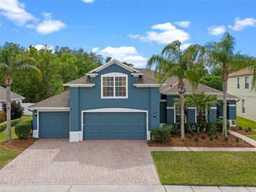 Charming two-story home featuring a three-car garage, lush landscaping, and a brick driveway at 820 Timber Isle Dr, Orlando, FL 32828