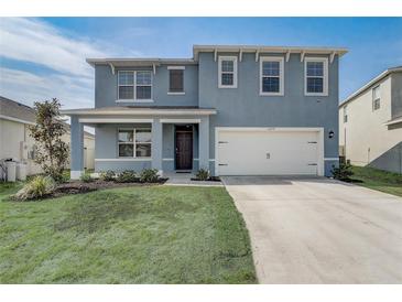 Charming two-story home featuring a well-manicured lawn, two car garage, and delightful exterior at 11279 Amber Ridge Dr, Zellwood, FL 32798