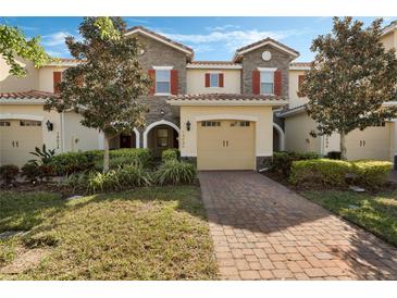 Inviting townhome with a well-manicured lawn and red brick driveway leading to a one-car garage at 14040 Helsby St, Orlando, FL 32832