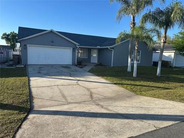 Charming single-story home with a well-maintained lawn, palm trees, and a two-car garage at 214 Magellan Dr, Kissimmee, FL 34758