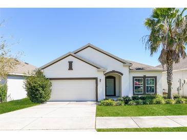Charming single-story home with a manicured lawn and a white exterior complemented by a neatly trimmed palm tree at 2430 Sanderling St, Haines City, FL 33844
