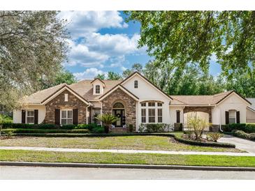 Charming single-story home featuring stone accents, a tile roof, and a well-manicured front lawn and landscaping at 25813 Feather Ridge Ln, Sorrento, FL 32776