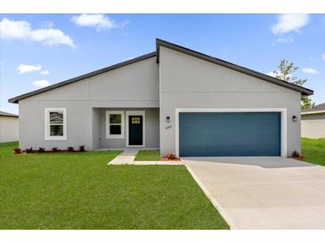Charming single-story home with a blue garage door, gray facade, and well-manicured lawn at 3984 Sw 151St St, Ocala, FL 34473