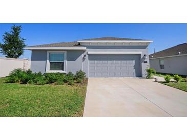 Charming single-story home with a gray exterior, a two-car garage, and a well-manicured lawn at 660 Silver Palm Dr, Haines City, FL 33844