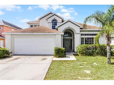 Charming two-story home featuring a manicured lawn, attached two-car garage, and inviting front entrance at 745 Riggs Cir, Davenport, FL 33897