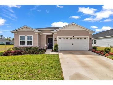 Attractive home exterior with a well-maintained lawn, a two-car garage, and landscaped garden beds at 7536 Sw 77Th Ave, Ocala, FL 34481