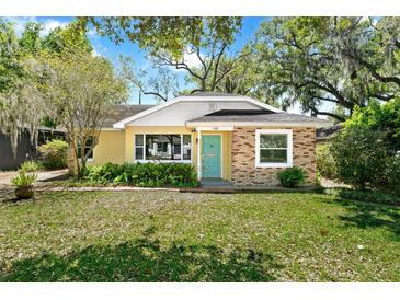Charming single-story home featuring a mix of brick and siding, a well-manicured lawn and a teal front door at 926 Mayfair Cir, Orlando, FL 32803