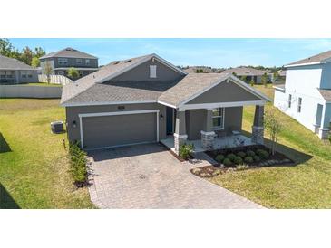 One-story home with a gray exterior, well-manicured lawn, and a brick driveway at 2837 Darlington Oak Ln, Ocoee, FL 34761