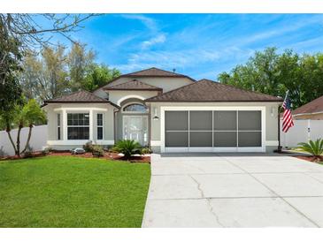 Charming single-Gathering home with well-manicured lawn, a screened garage, and a neutral-colored facade at 33215 Kaylee Way, Leesburg, FL 34788