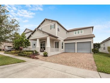 Charming two-story home with a covered front porch, two-car garage, and a brick driveway at 9870 Summerlake Groves St, Winter Garden, FL 34787