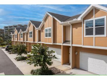 Row of tan two-story townhomes with white trim, garages, and small, newly planted trees at 106 Oceans Cir, Daytona Beach, FL 32118