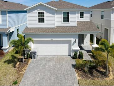 Charming two-story home featuring manicured landscaping, a paved driveway, and a two-car garage at 3273 Lilac Way, Davenport, FL 33897