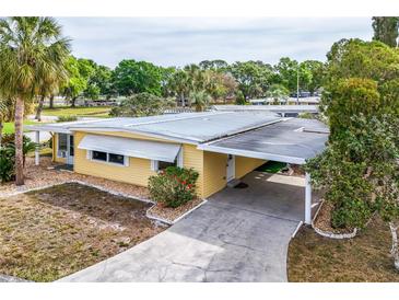 Aerial view of a well-maintained yellow home with an attached carport and lush landscaping at 726 Viking Ave, Tavares, FL 32778