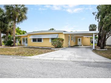 Inviting single-story home with bright yellow exterior and carport, complemented by a well-kept lawn and established landscaping at 726 Viking Ave, Tavares, FL 32778