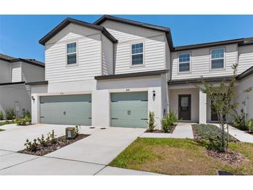 Inviting two-story townhome boasts a well-manicured front yard and attached two-car garage at 848 Poppy Ln, Dundee, FL 33838