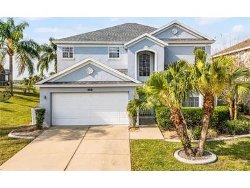 Charming two-story home with a two-car garage, landscaped yard, and tropical palm trees at 119 Horton Park Dr, Davenport, FL 33897