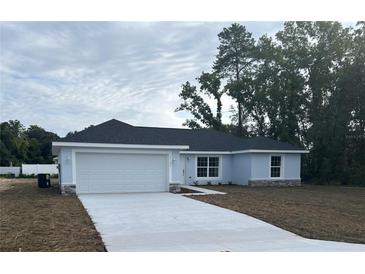 Charming one-story home with a two car garage, stone accents, and a well-manicured lawn at 13075 Se 35Th Ct, Belleview, FL 34420