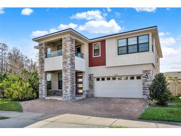 Two-story home boasting a contemporary design, with stone accents and a brick-paved driveway at 2200 Rapollo Dr, Kissimmee, FL 34741