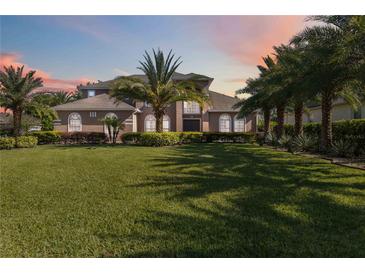 Elegant two-story home with a manicured lawn and mature palm trees, showcasing its curb appeal under a colorful sky at 6761 Scimitar Ave, Orlando, FL 32812