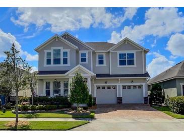 Two-story home featuring a two-car garage, landscaped yard, and covered front porch at 8225 Corkfield Ave, Orlando, FL 32832